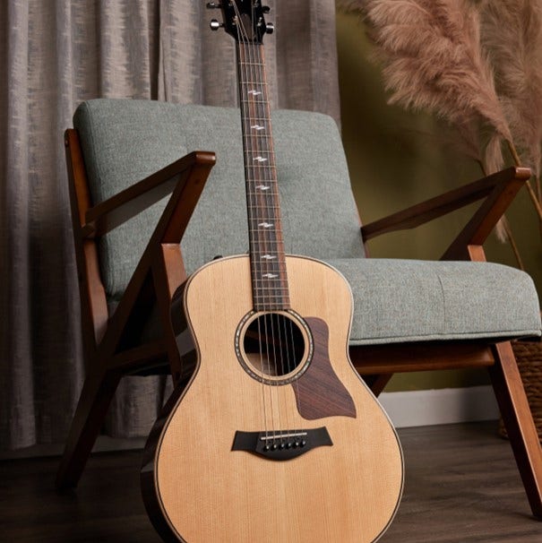 A Taylor acoustic guitar leaning against a chair