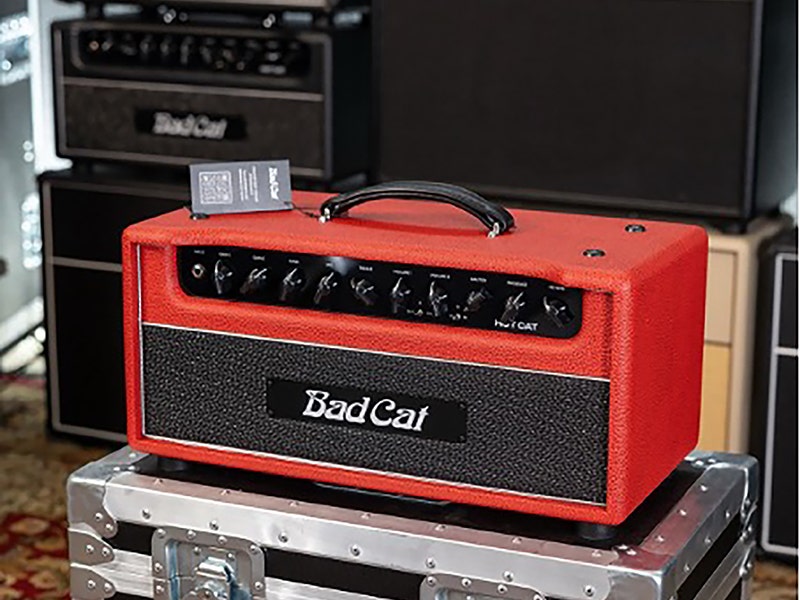 Bad Cat Hot Cat guitar amplifier head in red tolex covering, displayed on a flight case surrounded by other amplifiers
