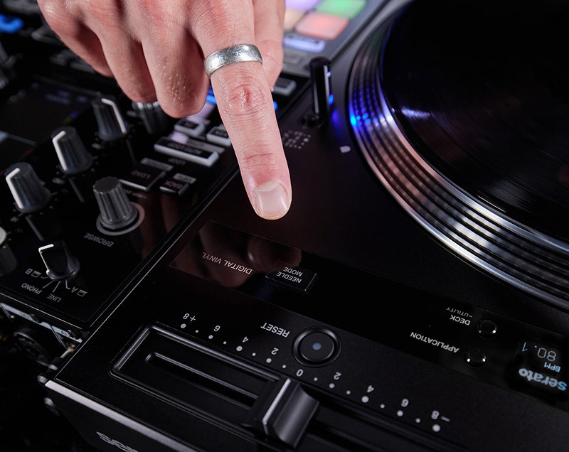 Close-up of a DJ’s hand interacting with the touchscreen display on a modern turntable-style DJ controller.