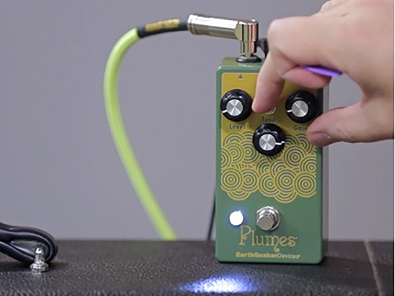 EarthQuaker Devices Plumes overdrive guitar pedal in green with Level, Tone, and Gain knobs, being adjusted by hand