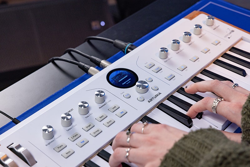 A girl playing a digital piano keyboard at a wooden desk in a home musica practice space