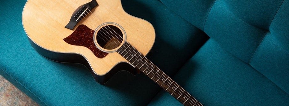 A Taylor acoustic guitar laying on a couch