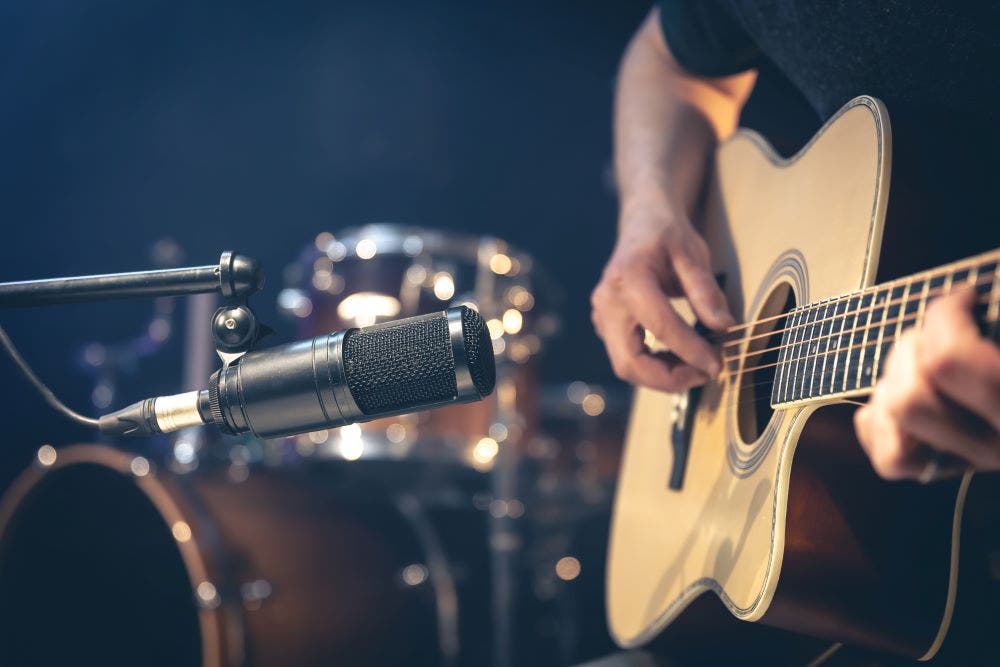 person playing an acoustic guitar in front of a microphone