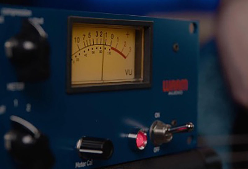Audio processor with VU meter in a professional audio setup.