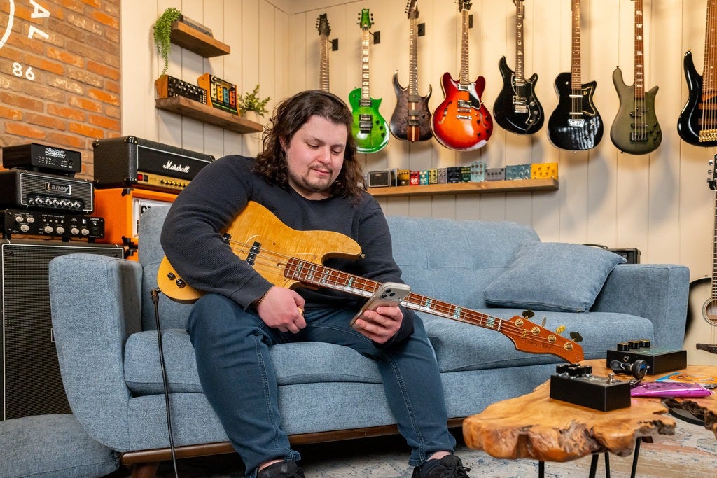 Bassist sitting on a couch holding a bass
