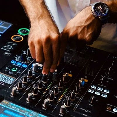 A DJ adjusting knobs and faders on a mixer