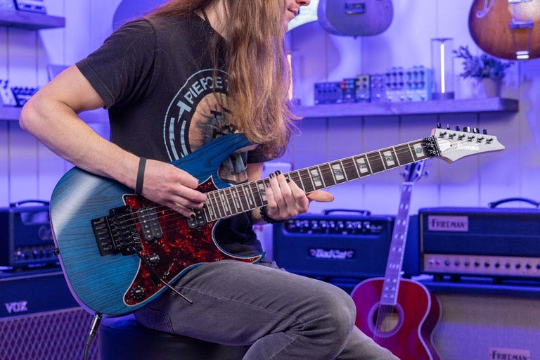 Photo of a guitarist playing an Ibanez electric guitar in the AMS studio
