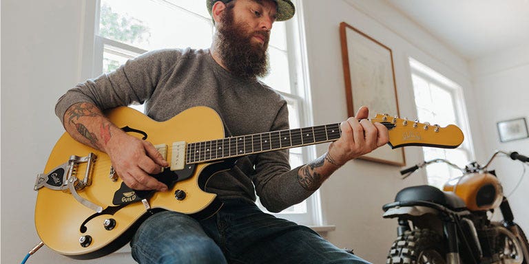 Photo of a guitarist playing a Guild hollow body electric guitar