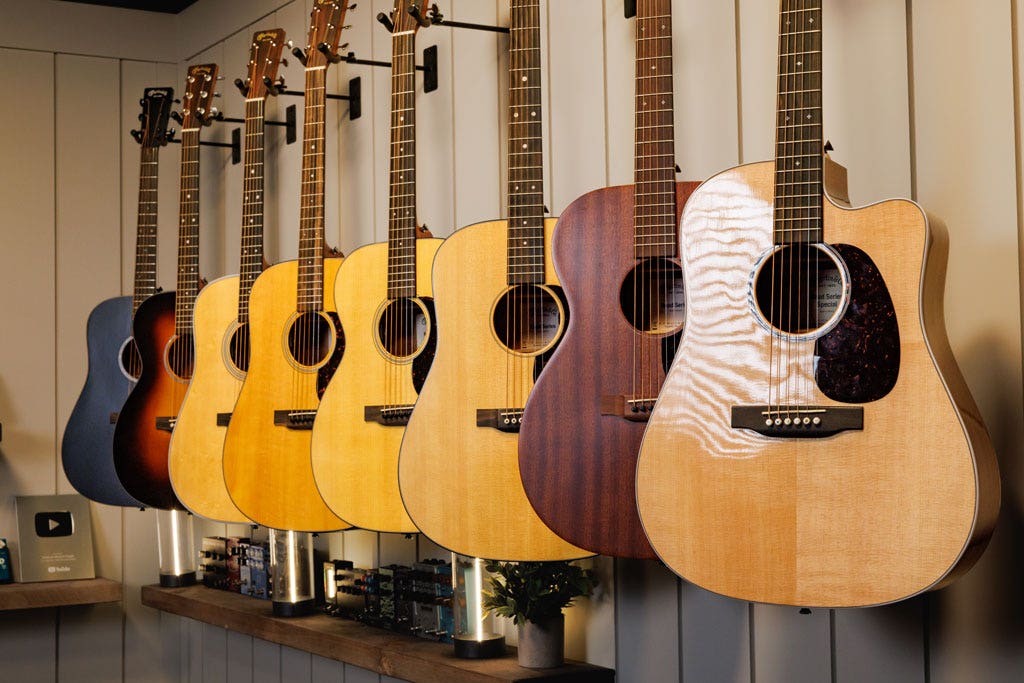 Photo of a wide range of Martin acoustic guitars hanging on a wall.