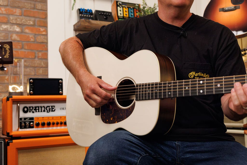 Photo of a man playing a Martin dreadnaught acoustic guitar in the AMS studio