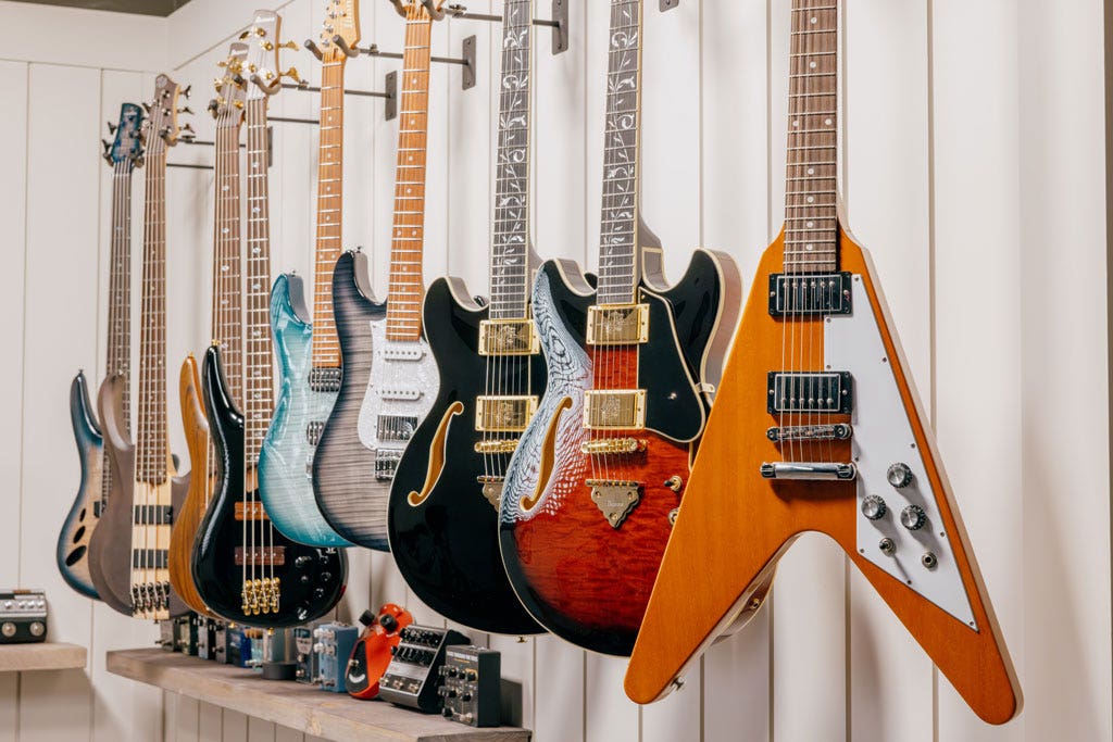 A variety of guitars hanging on a wall.