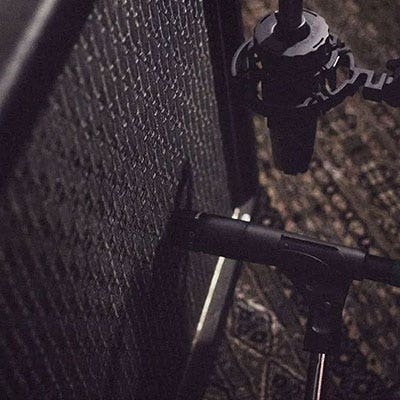 Image of a microphone placed next to a guitar amplifier.