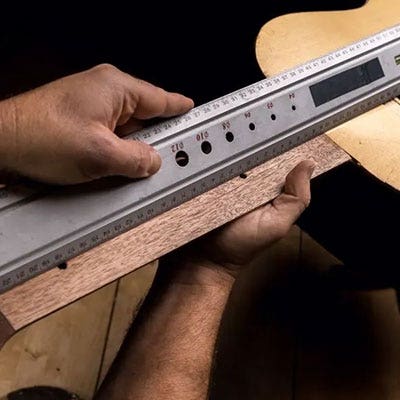 Image of a man measuring the scale length of a guitar.
