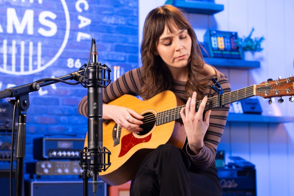 Microphones recording a woman playing guitar