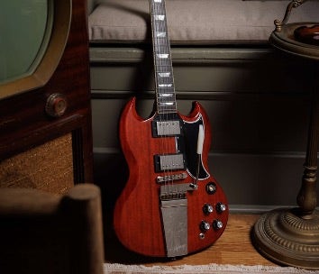Red Epiphone SG resting by vintage TV