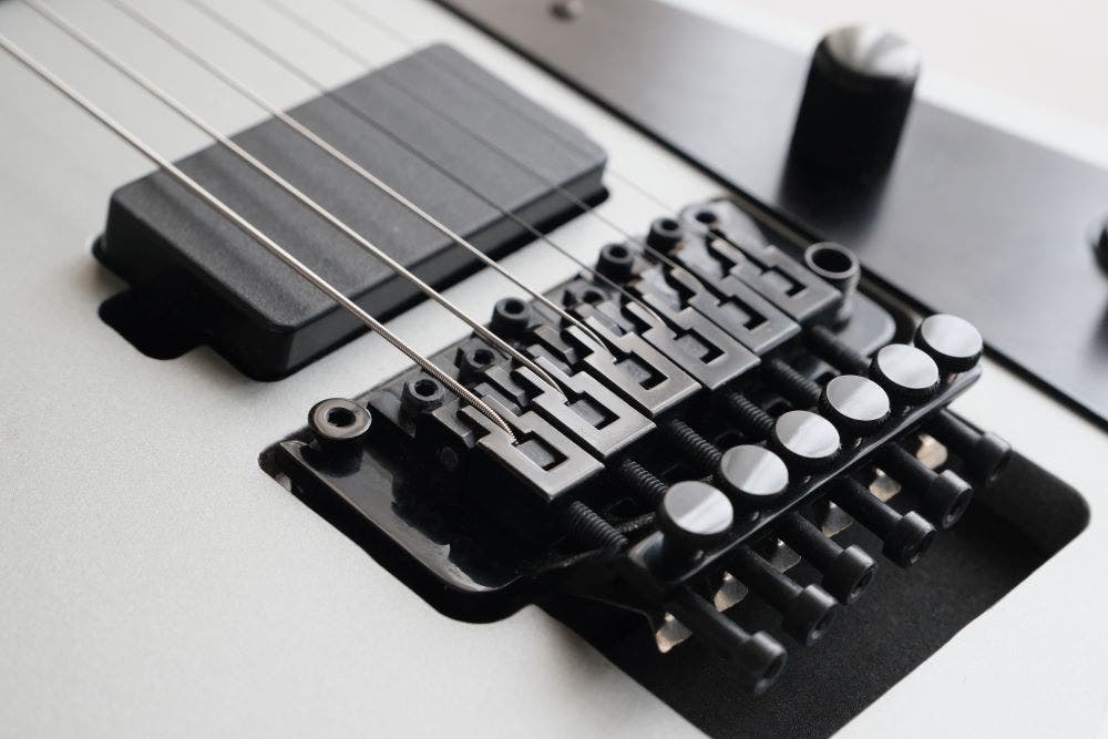 Floyd Rose locking tremolo guitar bridge on white guitar with active pickups