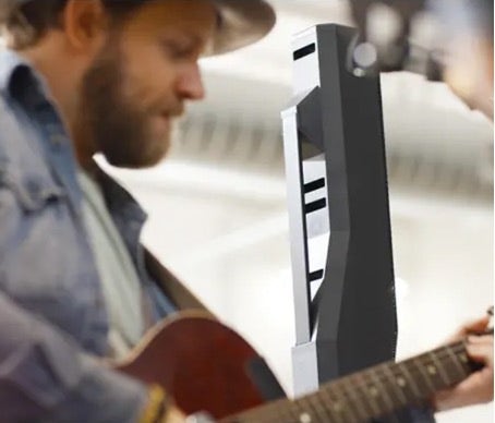 A musician in a hat plays an acoustic guitar near an Electro-Voice speaker.