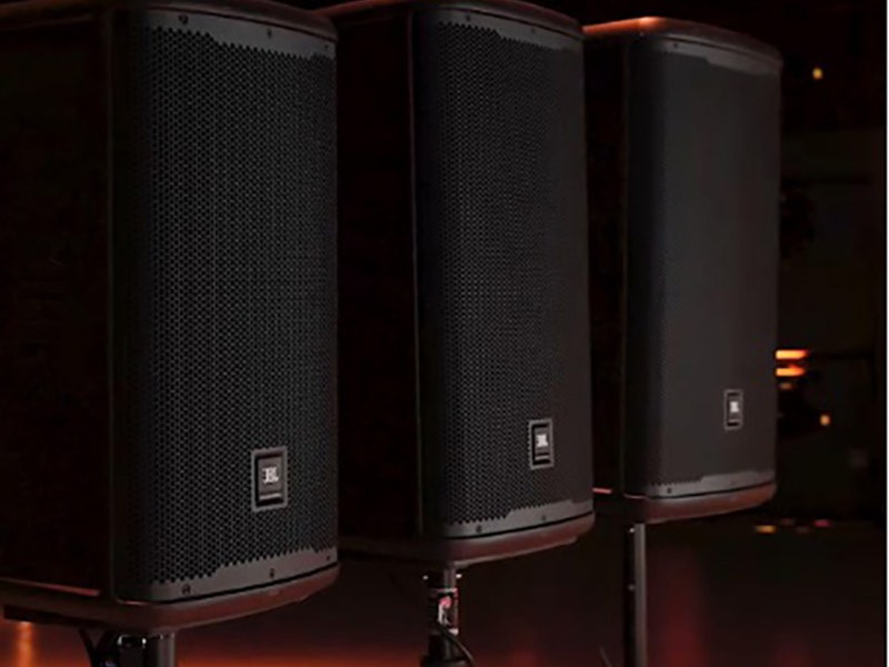 Row of portable PA speakers in a dimly lit setting.