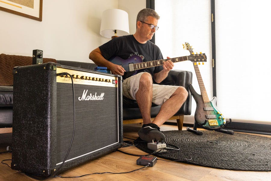 A guitarist playing a Gibson electric hooked up to a Marshall amp with an assortment of pedals