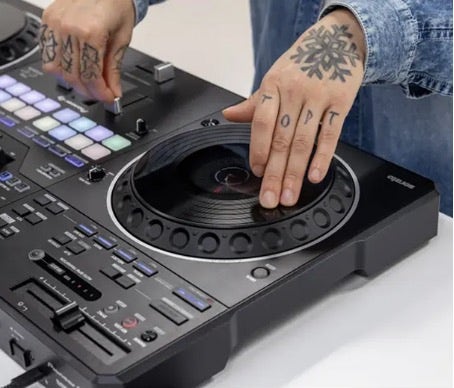 Close-up of tattooed hands operating a standalone DJ controller.